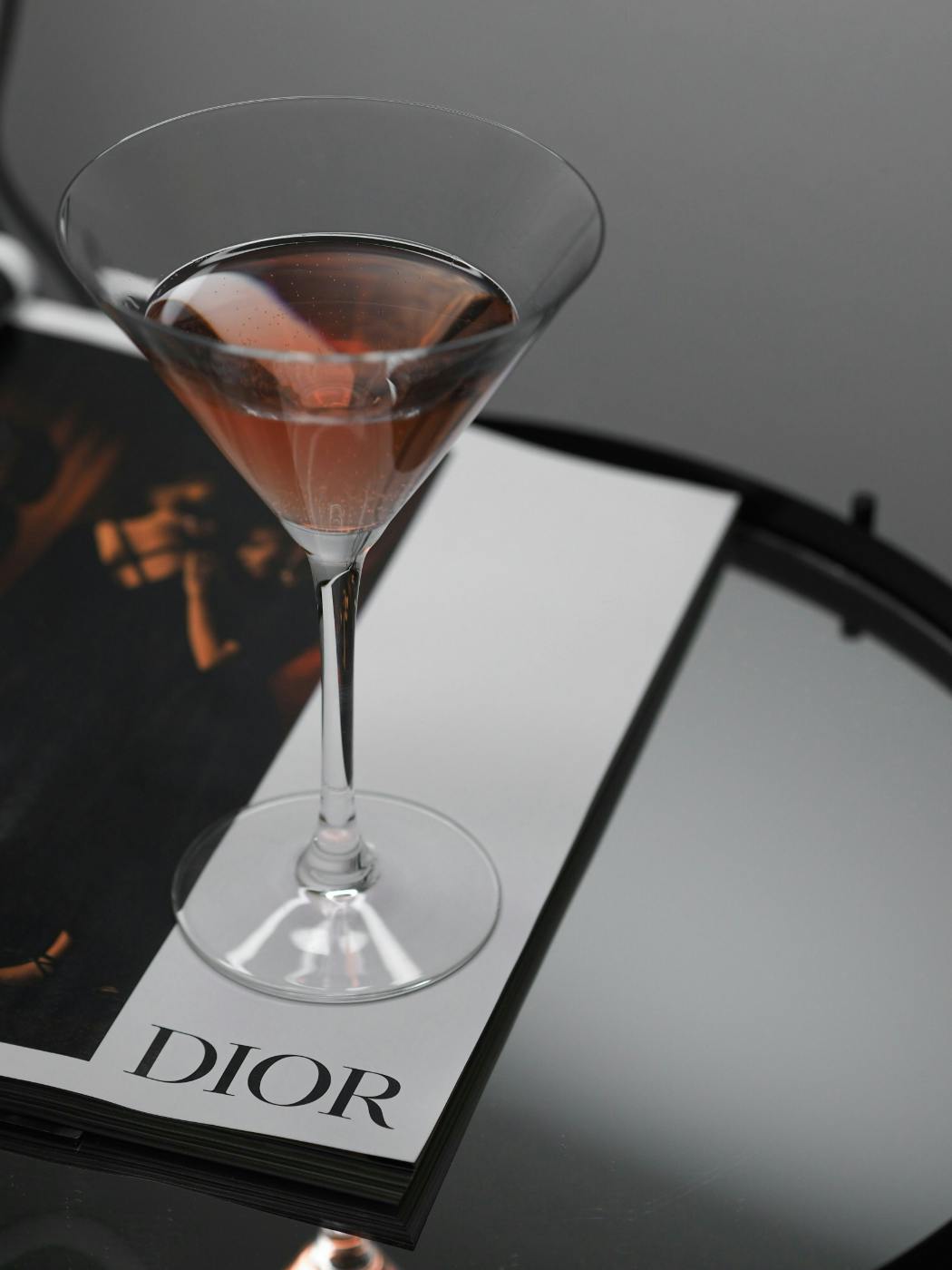 A Cosmo cocktail sitting on a magazine page that reads DIOR