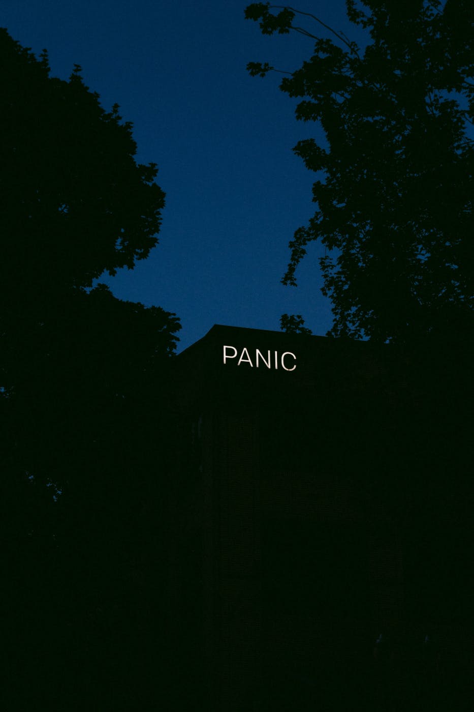 The silhouette of a building at night with a lighted sign reading PANIC