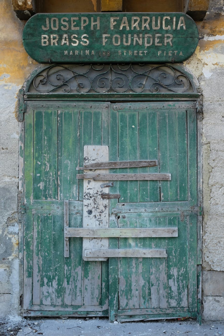 A large worn green door with a sign above it reading: Joseph Farruccia Brass Founder