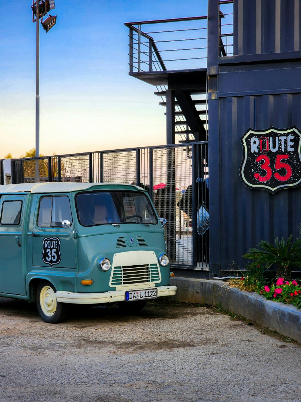 An old bblue VW Microbus with a route 35 sticker on it parked next to a building with same sticker