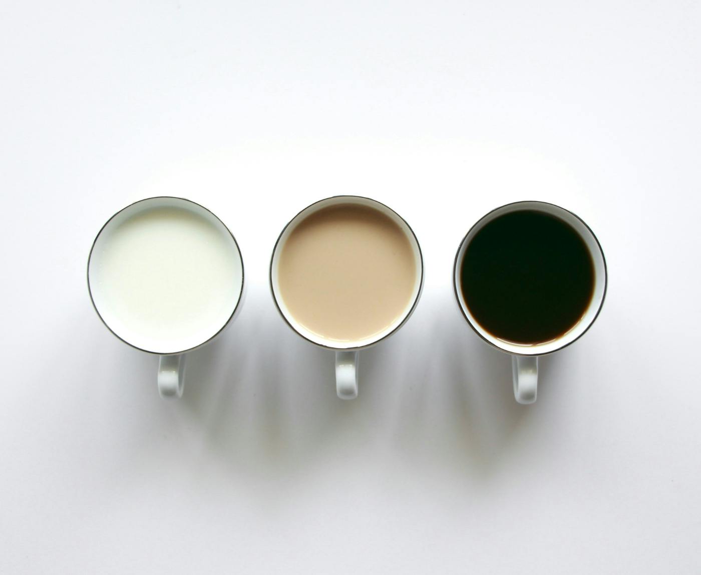 3 coffee cups with liquid in them, white, brown and black liquids
