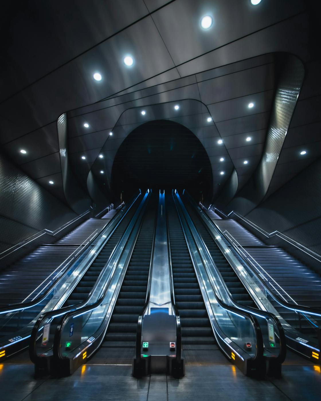 Two flights of stairs and four escalators leading up to a black opening