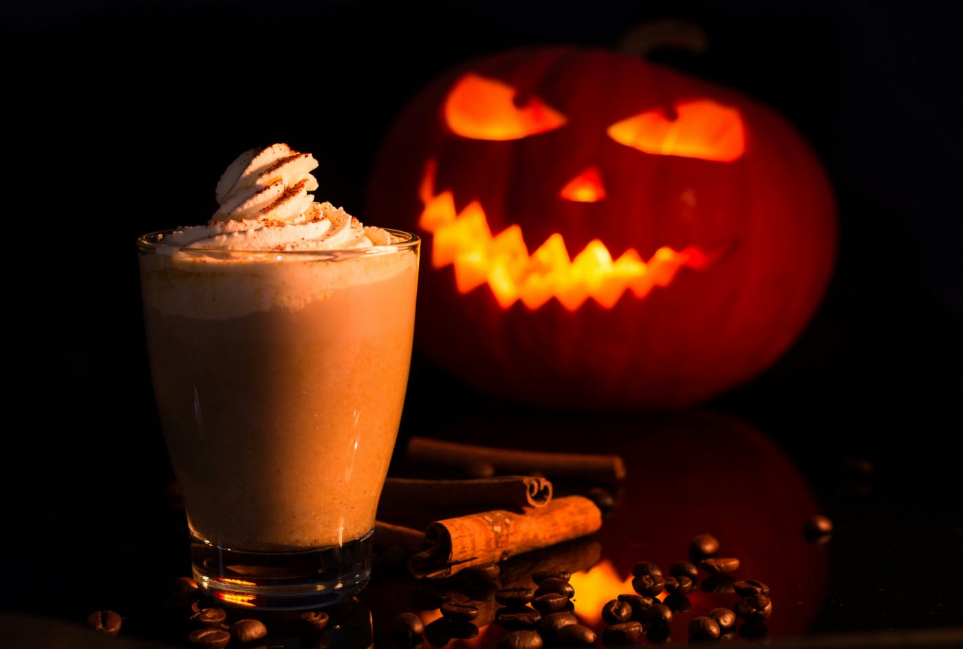 A jack-o-lantern and a pumpkin spiced latte on a table