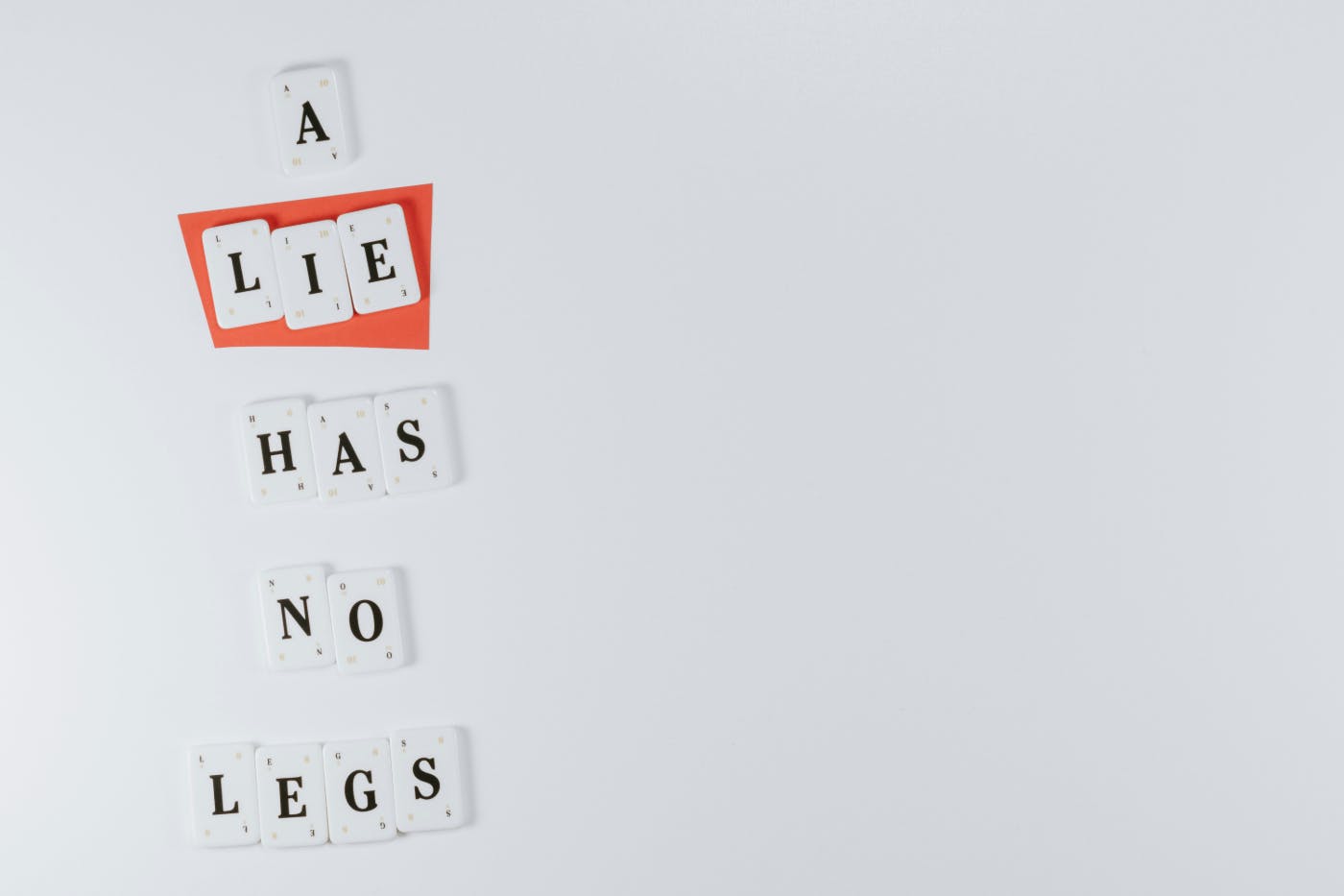 White lettered tiles spelling out A lie Has No Legs, the word lie is on a red background