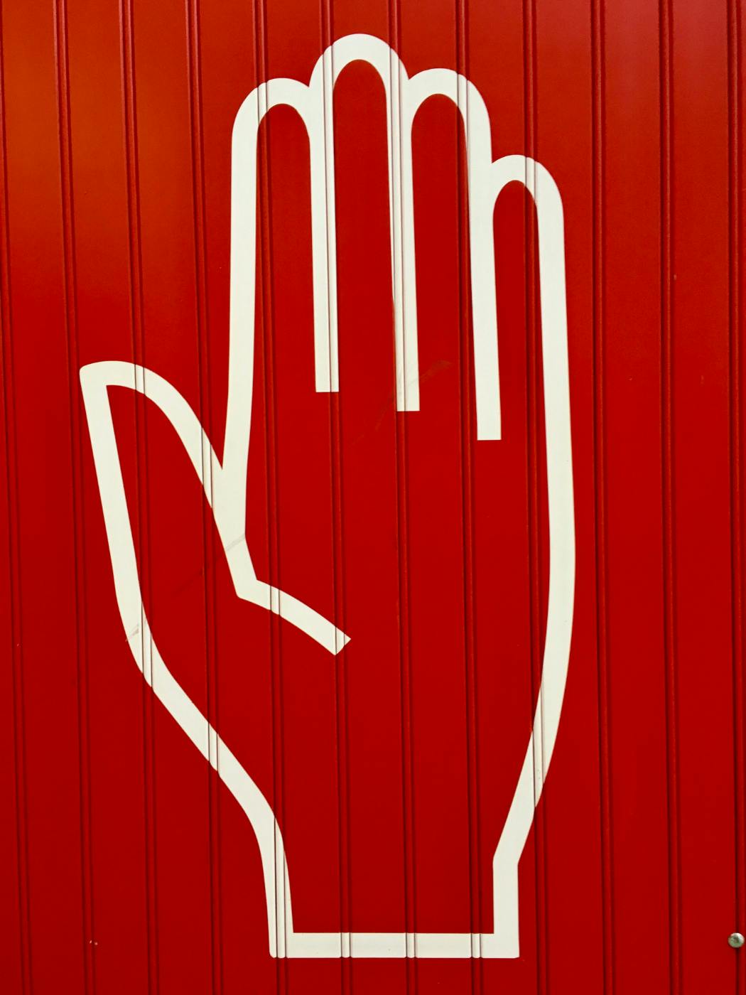 A red wall with the white outline of an open hand
