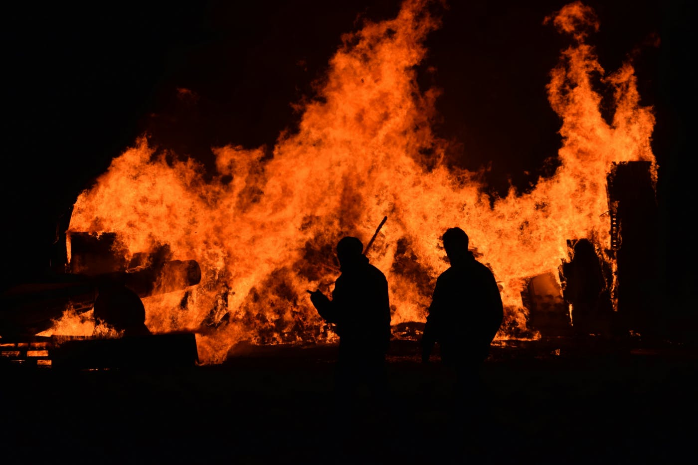 People walking by a burning structure