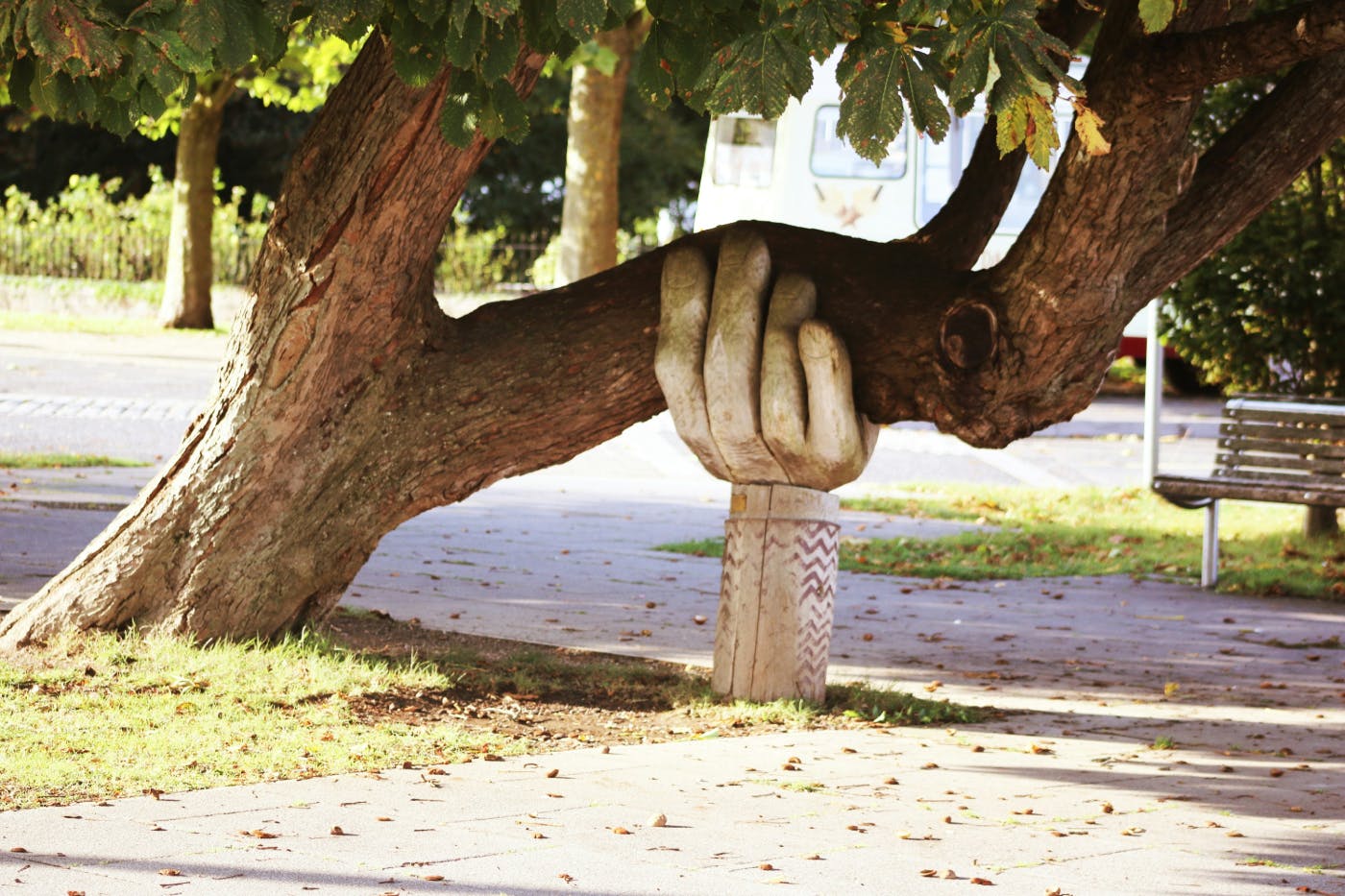 A leaning tree being supported by a giant carved hand