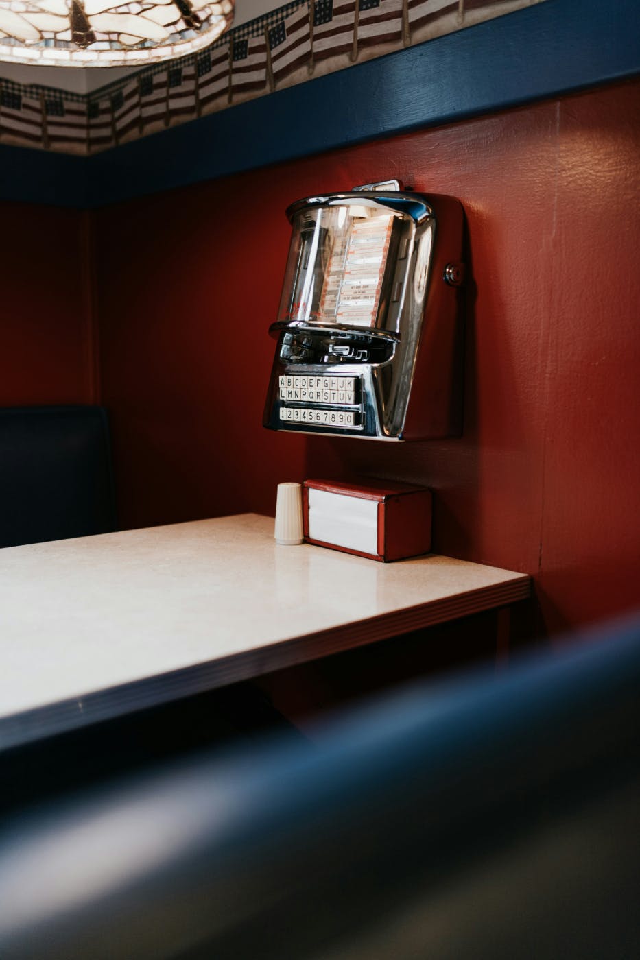 A classic diner booth with a wall mounted juke box