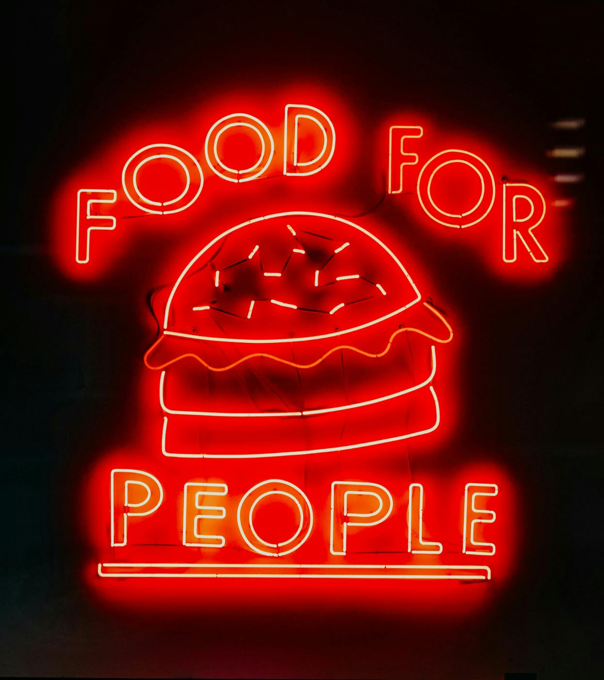A red neon sign with a burger and the words Food For People