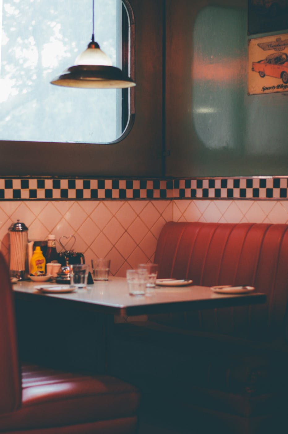 Corner table in a classic diner with red leather bench seats and black and white checked tile