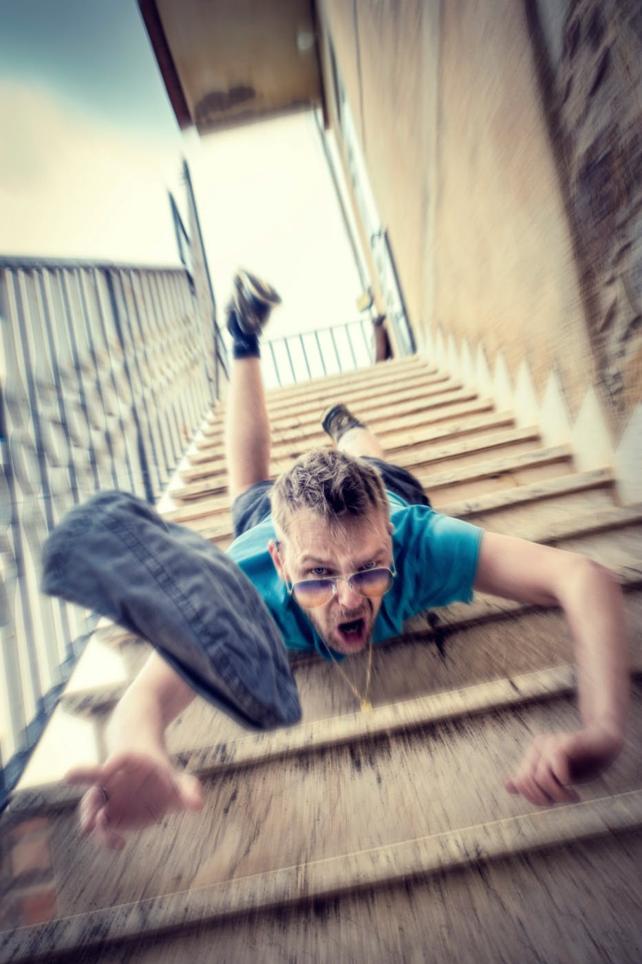 A man falling headfirst down a flight of concrete stairs
