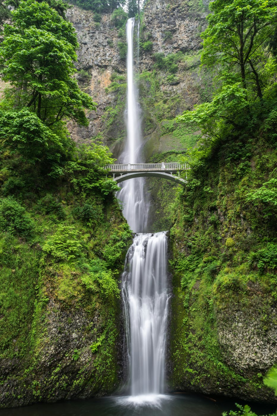 A bridge over a waterfall in the woods