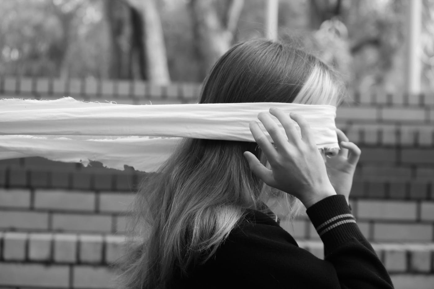 A woman with a white strip of fabric over her eyes holding her back