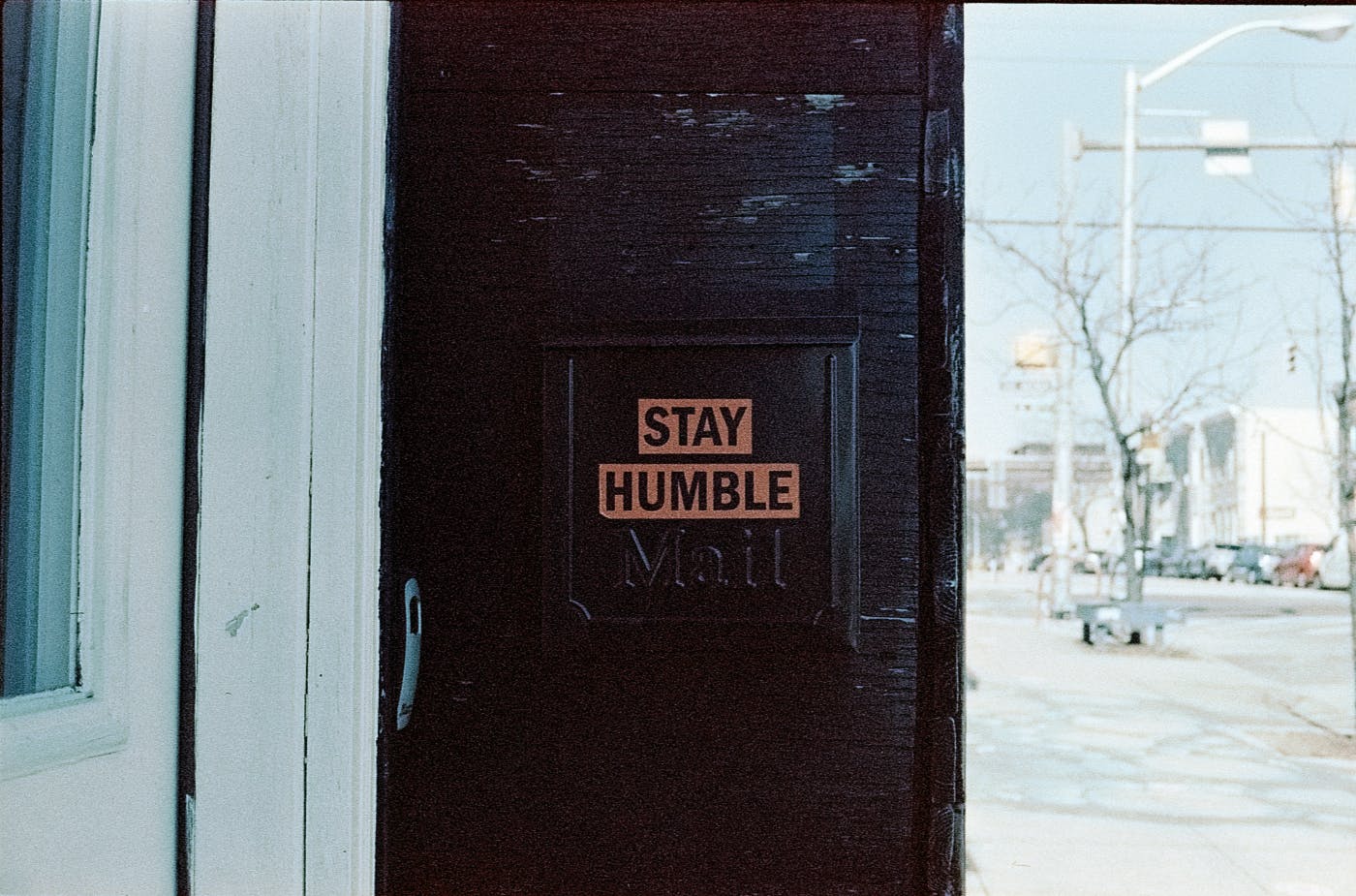 A black door with a sign that says Stay Humble