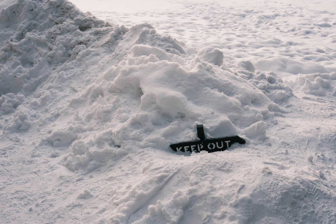 A keep out sign almost completely buried in snow