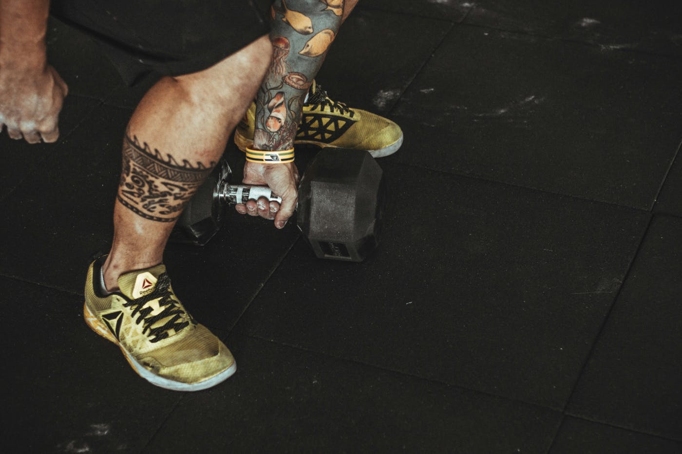 Heavily tattooed man lifting a hand weight
