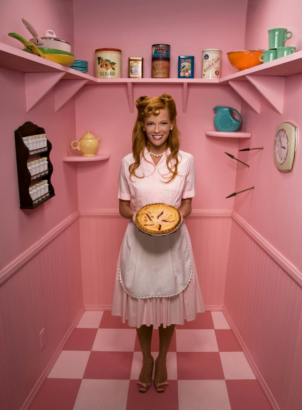 A "tradwife" holding a pie in a pink pantry