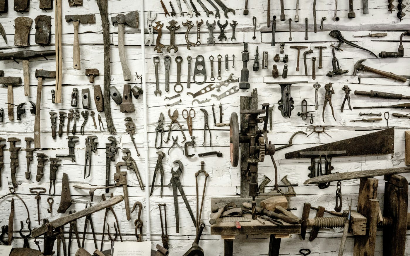 a wood wall painted white covered with old hand tools