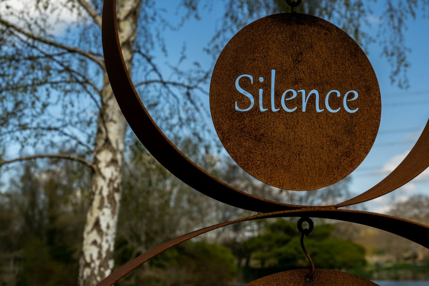 A rusted metal sign with the word Silence cut out of it