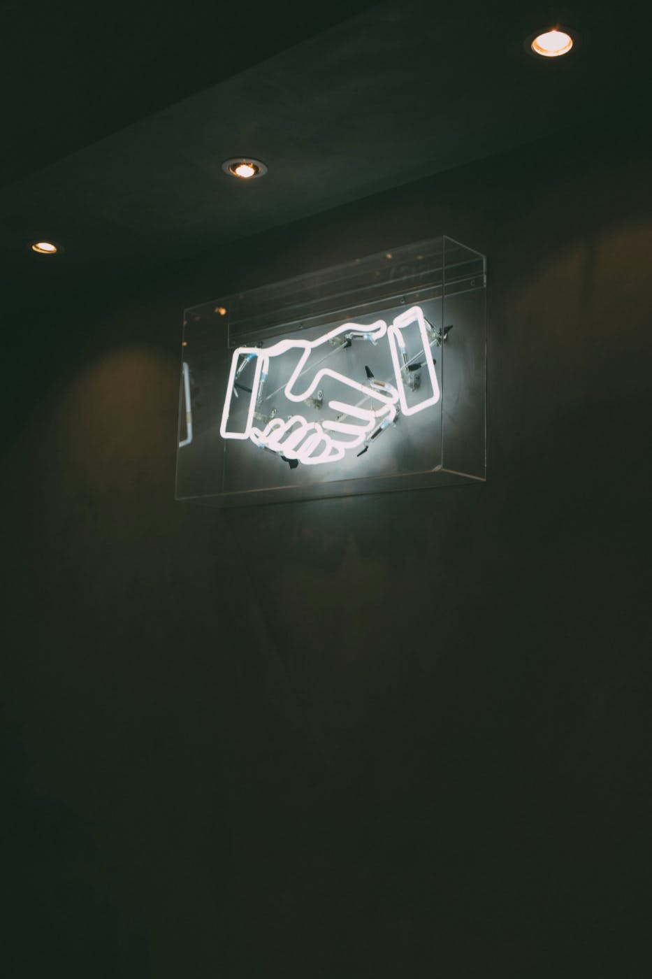 A white neon sign showing a handshake