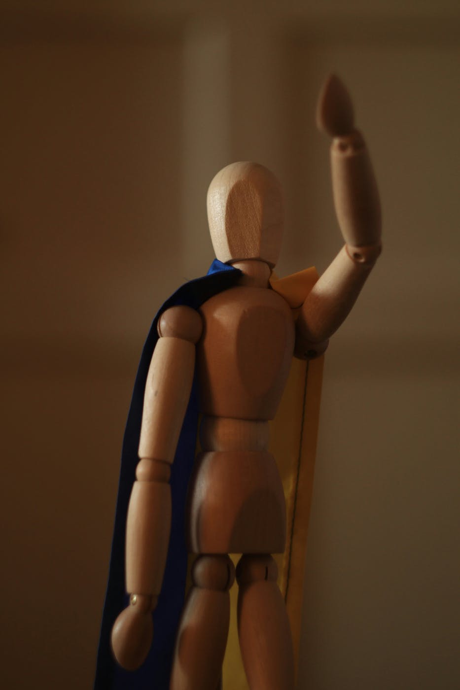 An artists mannequin wearing a blue cape and waving