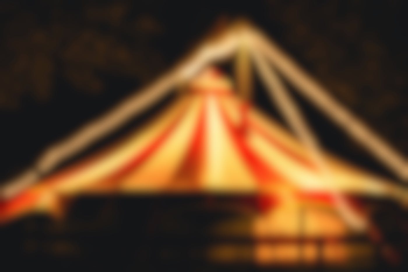A large red and white circus tent with strings of lights