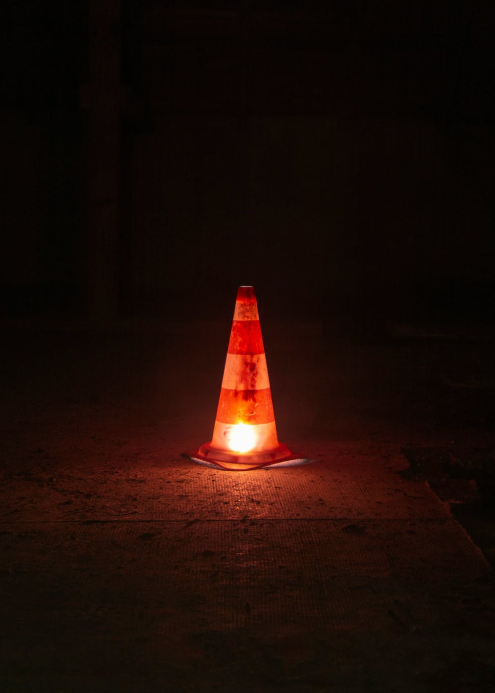 A traffic cone with a light under it at night