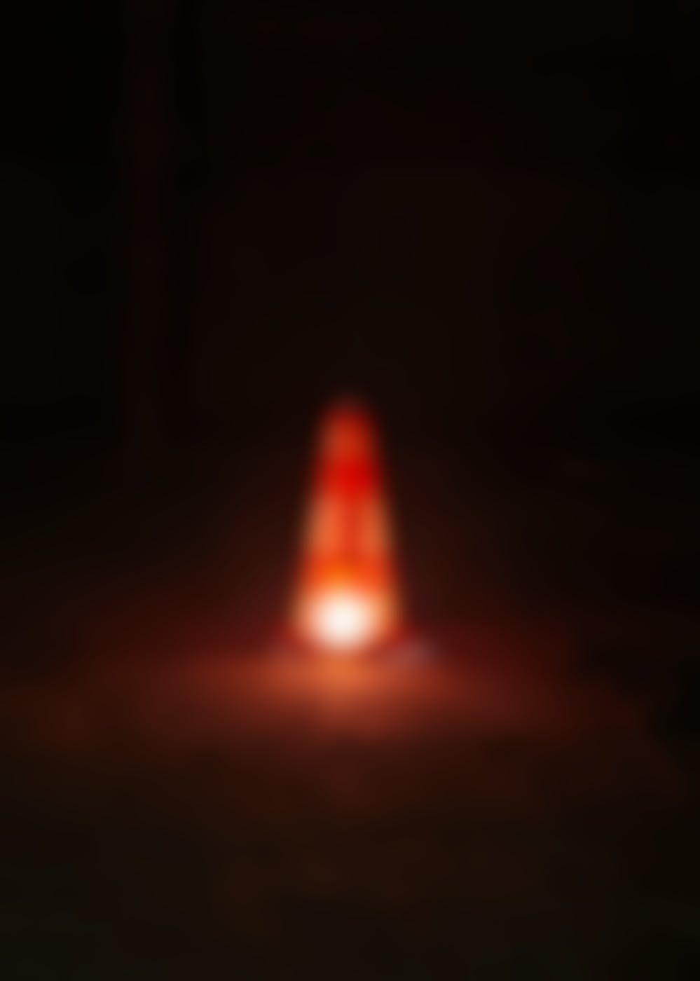 A traffic cone with a light under it at night