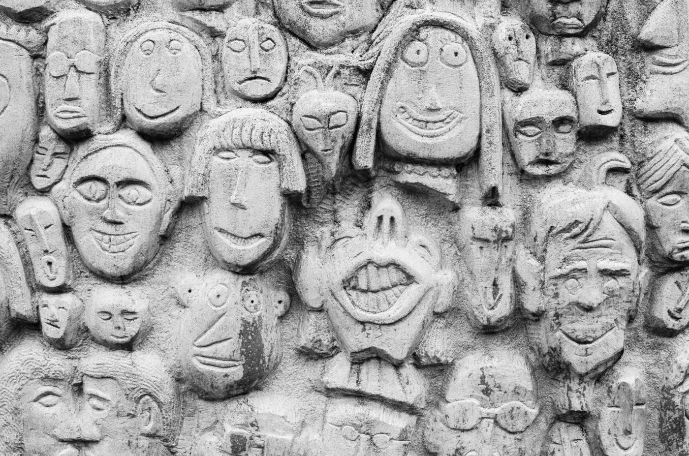 A variety of faces carved in a concrete wall