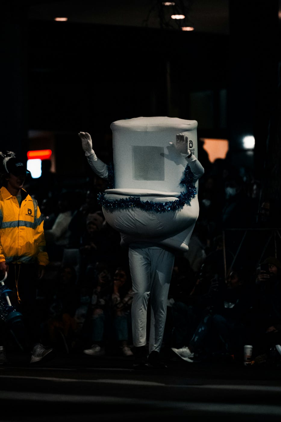 A person dressed as a toilet walking the street at night