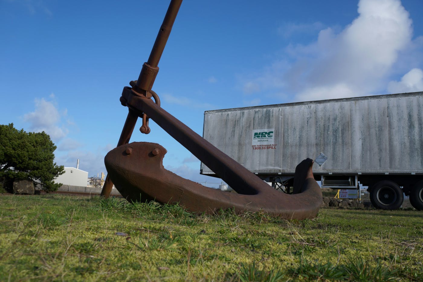 A giant ship's anchor in a field by a semi-truck