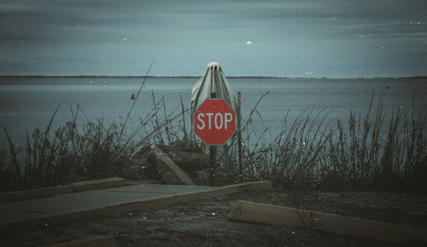 A ghost above a stop sign in a parking lot near the ocean