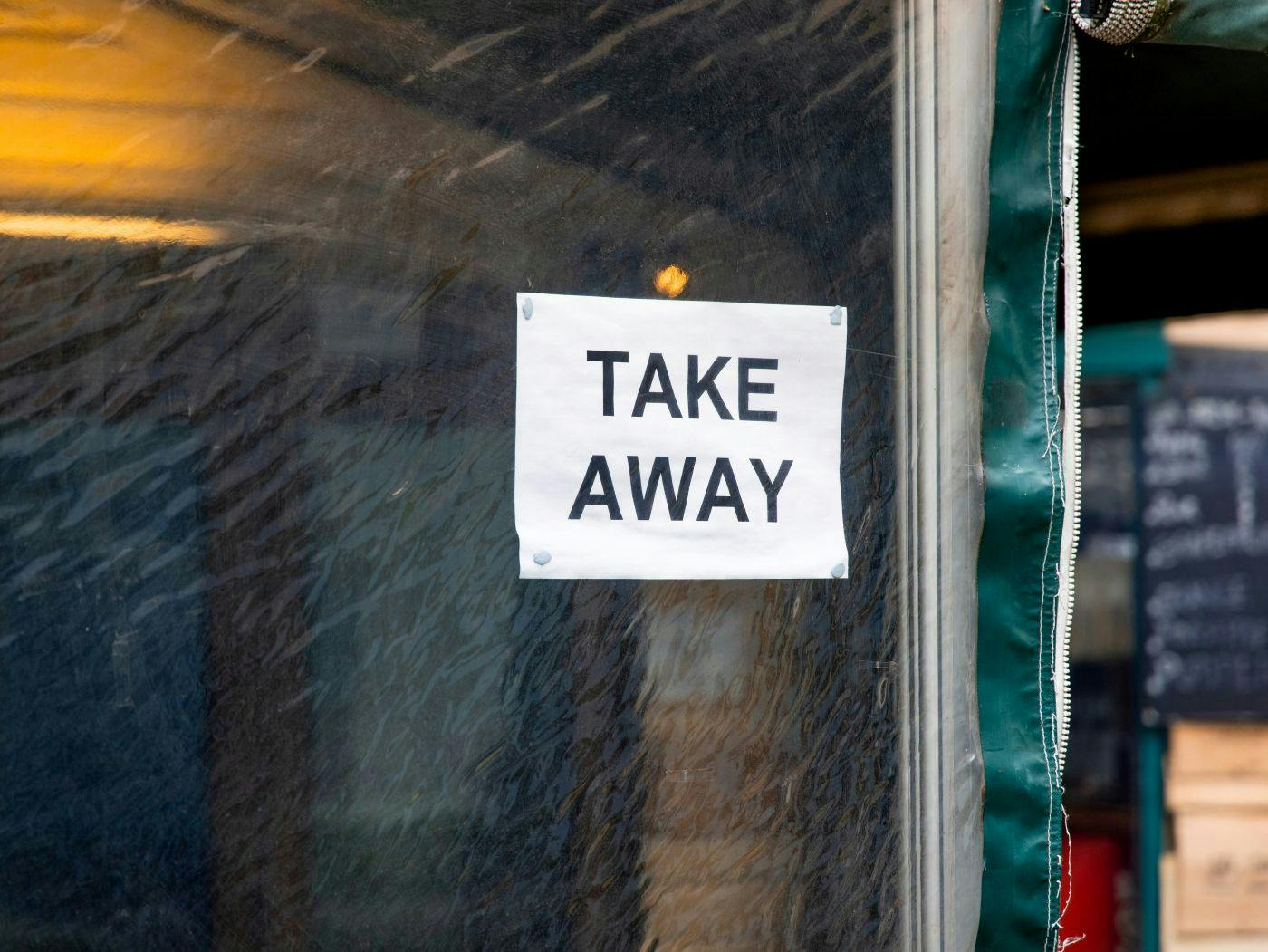 A small sign on a shop window reading Take Away