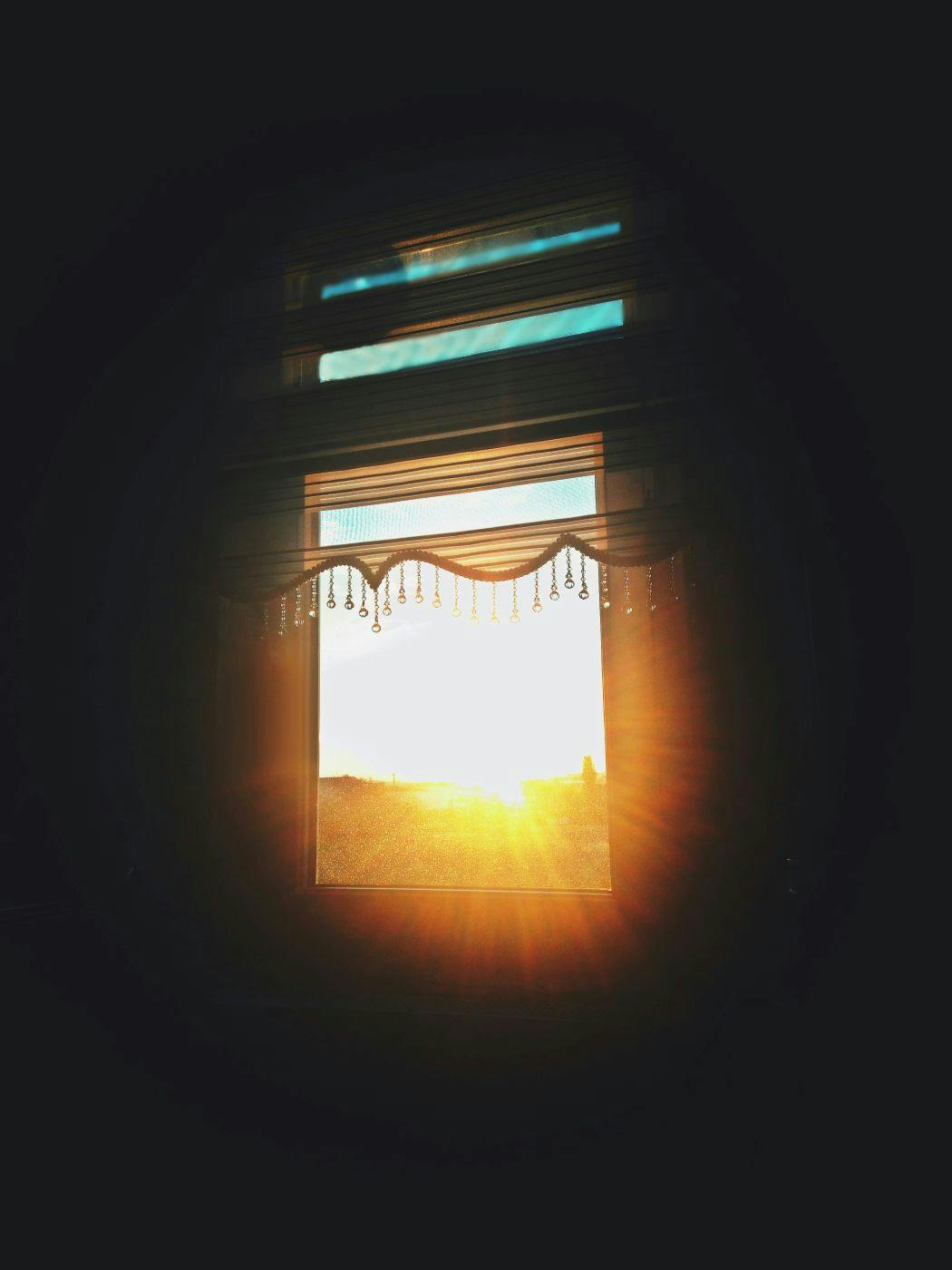 Sunrise through a window with frilled curtains