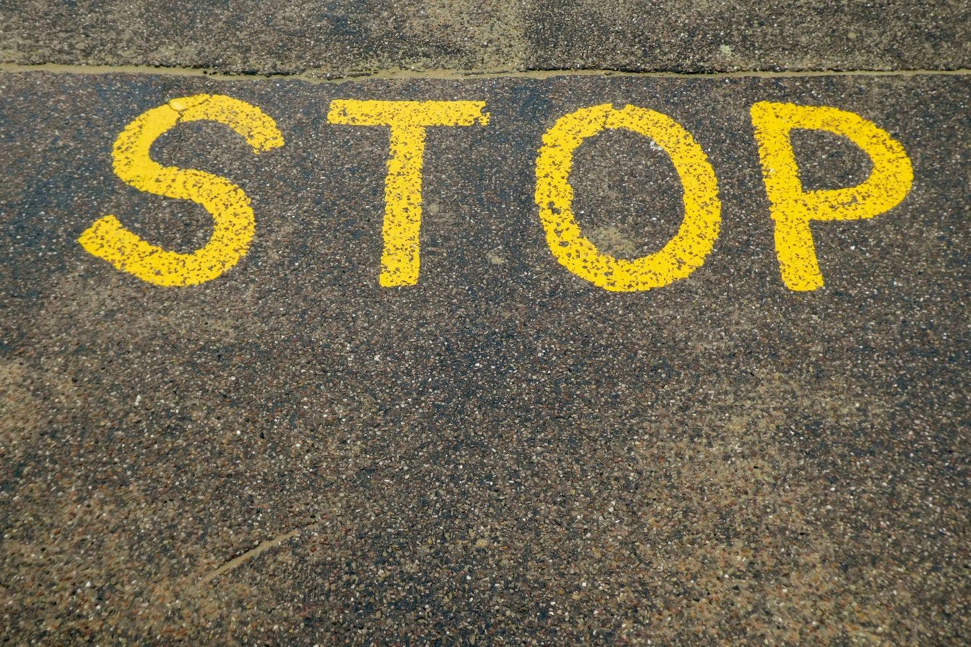 Stop written in yellow paint on a street