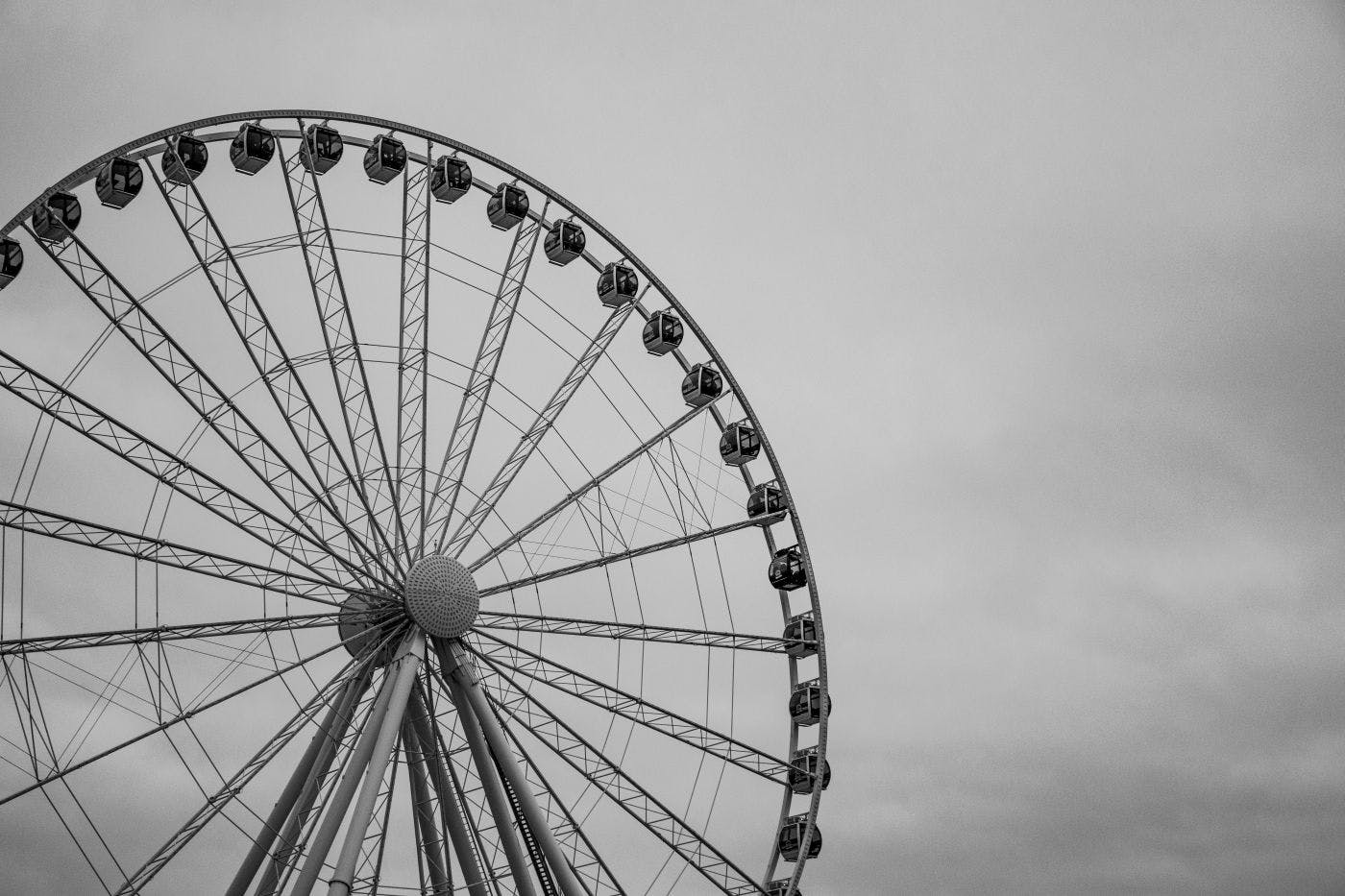 Black and white of a Ferris Wheel against a cloudy sky