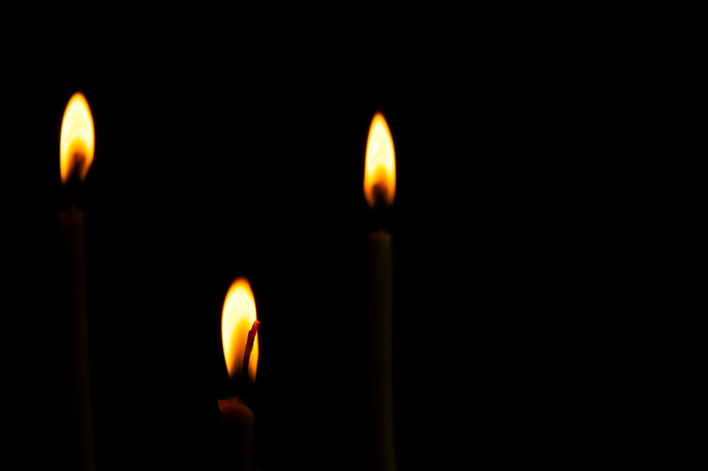 Three lit candles in the darkness