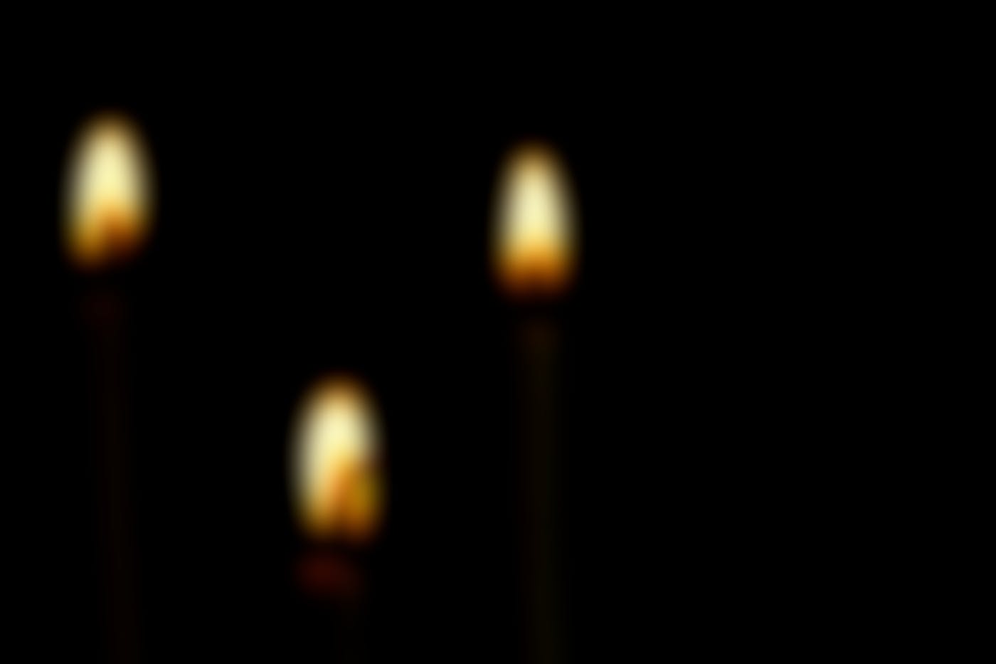 Three lit candles in the darkness