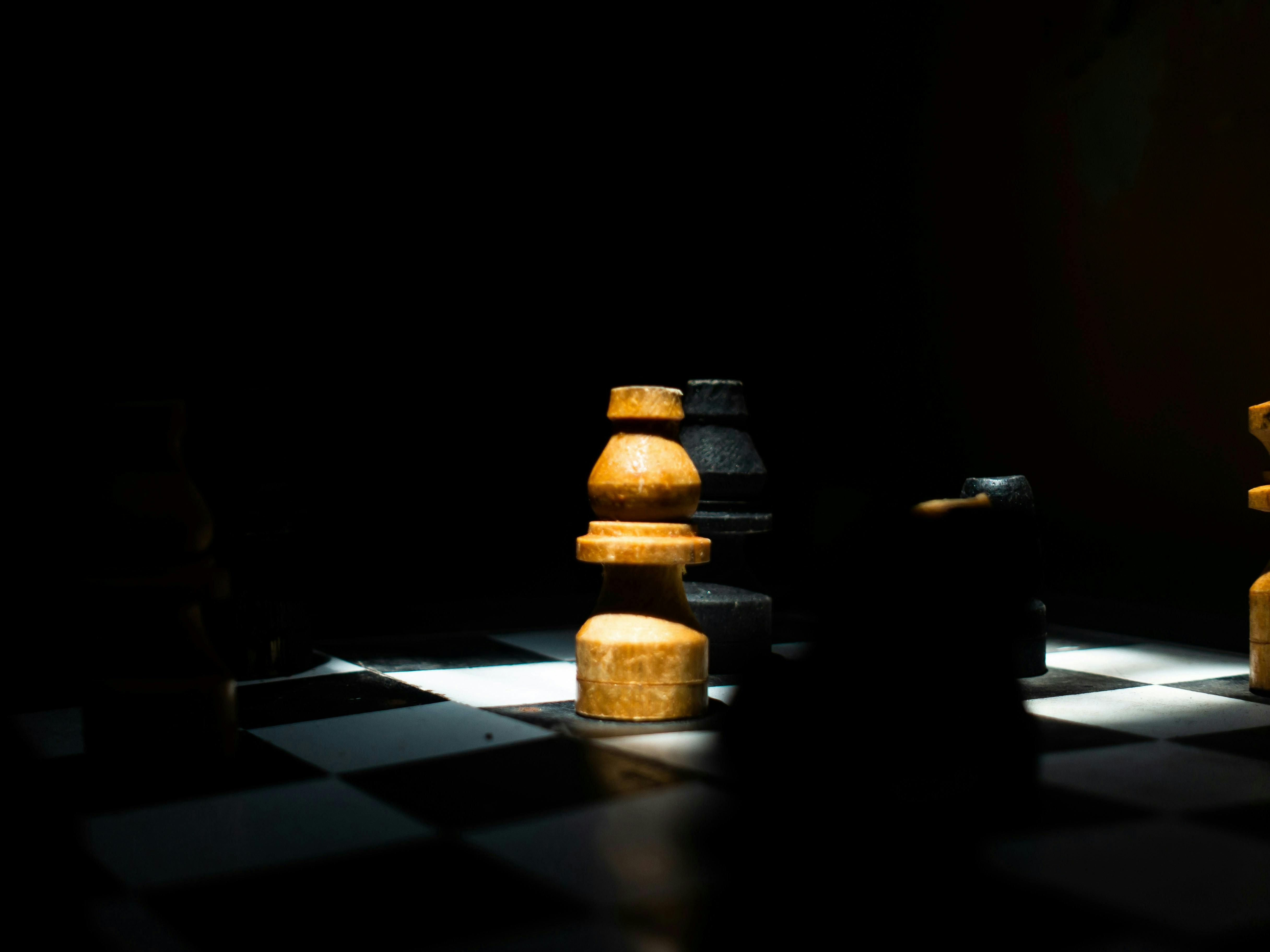 A chess game in dim light with black and yellow pieces