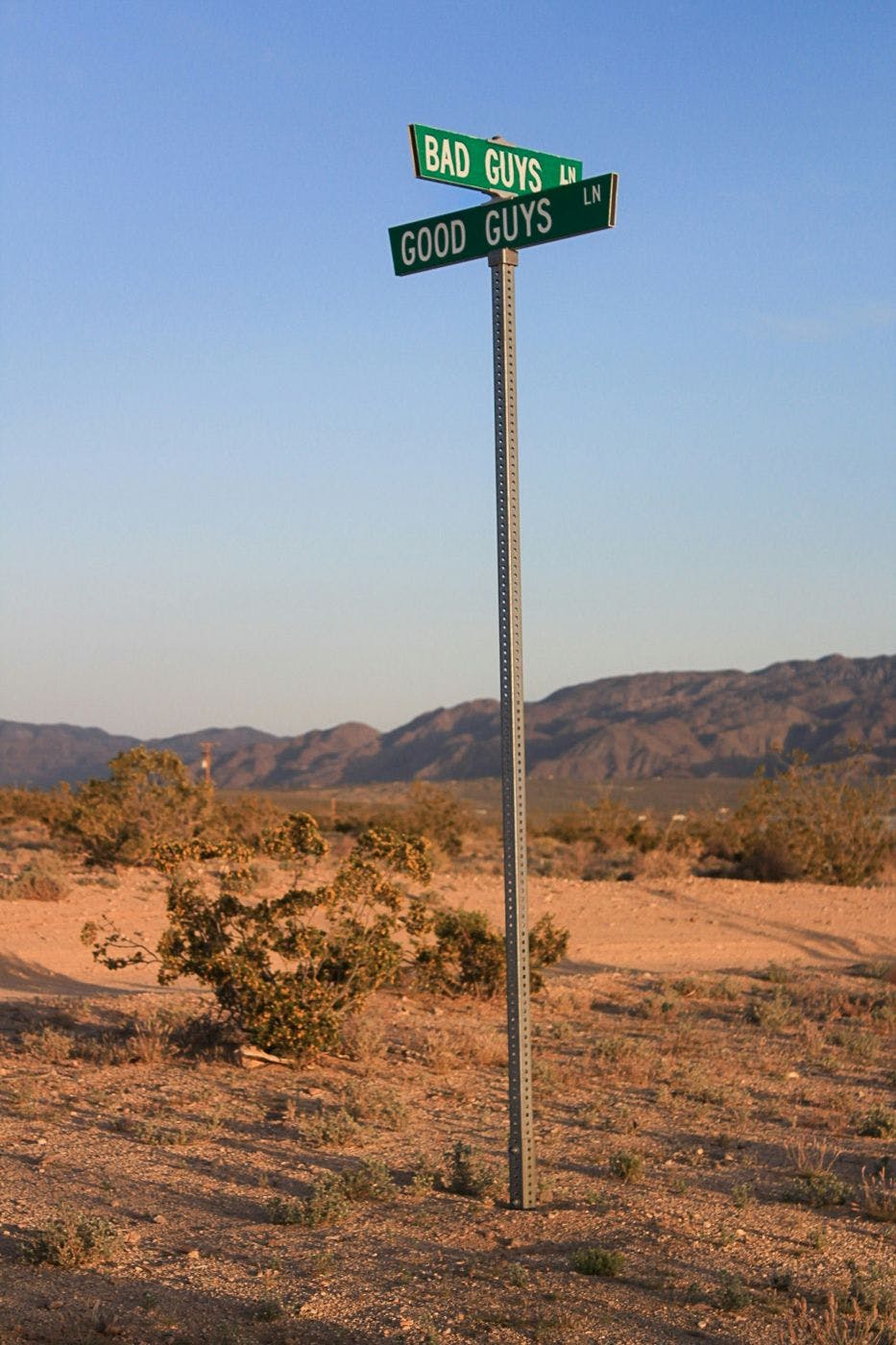 A signpost in the middle of the desert, two street signs: Bad Guy Street & Good Guy Street