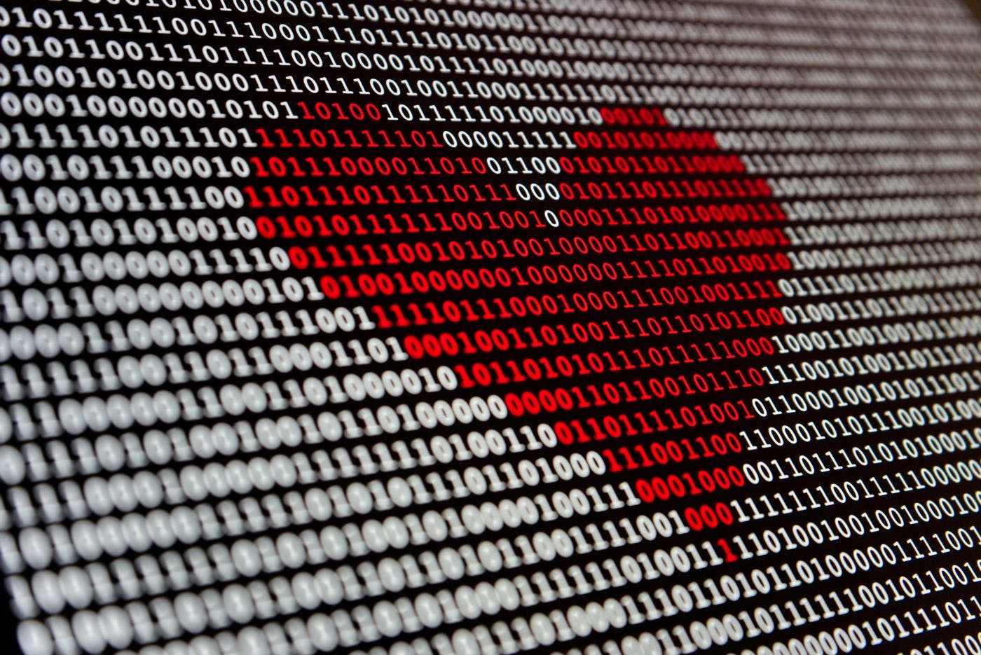 A screen covered with 1s and 0s and a red heart drawn over the middle