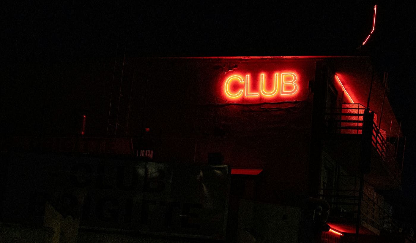 A dark alley and a red neon sign reading CLUB