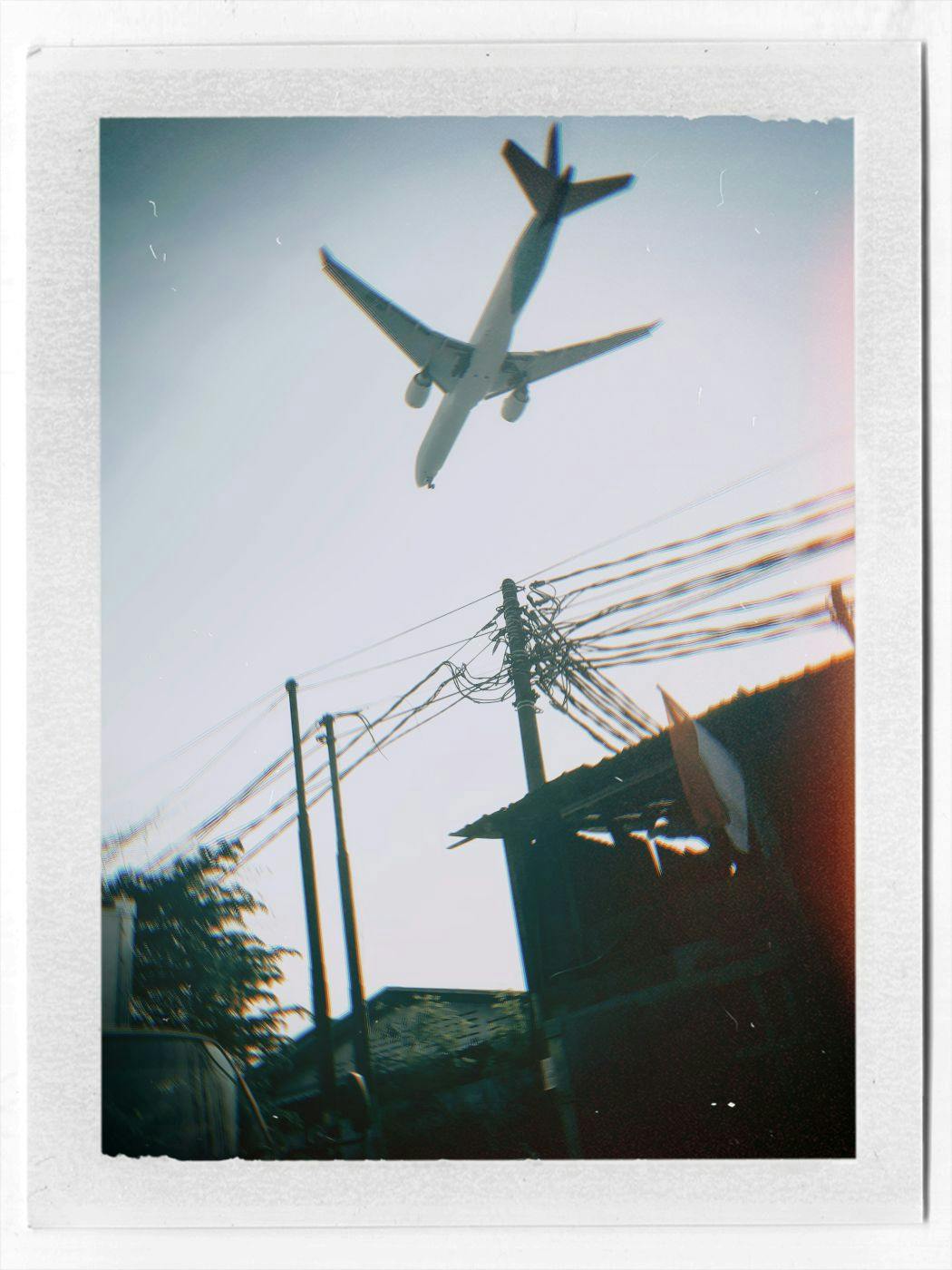 A Polaroid of a jet flying low over a suburban neighborhood