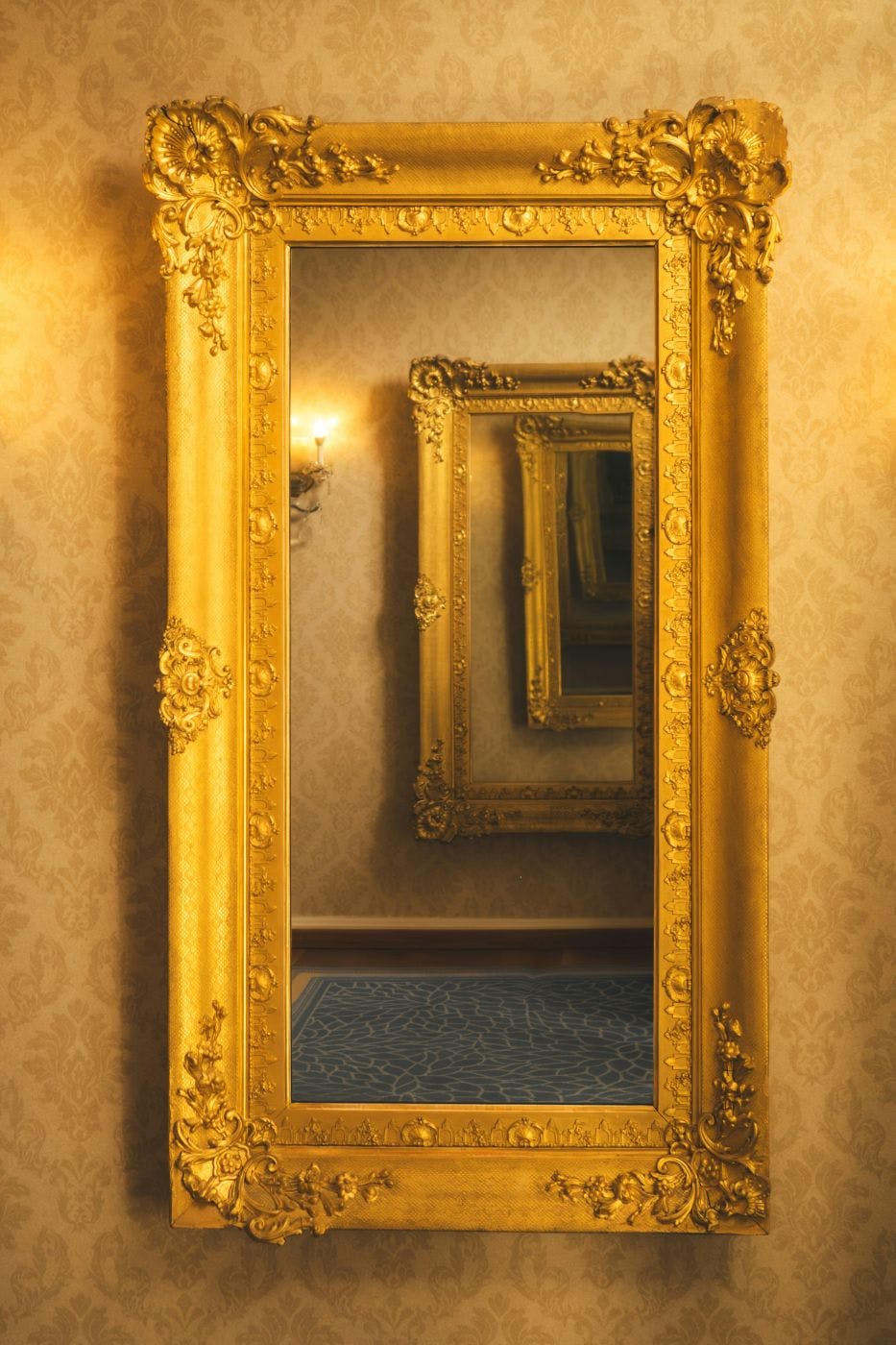 A gold framed mirror reflecting a gold framed mirror reflecting a god framed mirror, etc