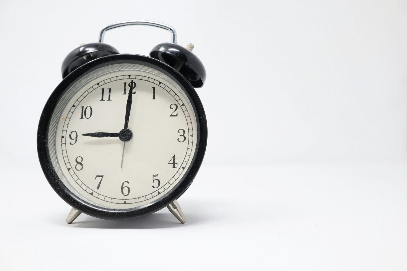 A classic black and white alarm clock set to 9
