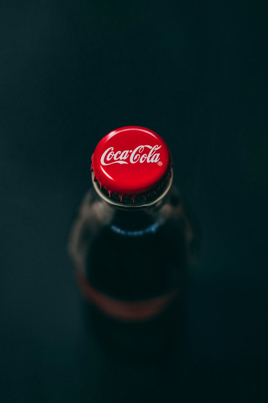 A bottle of Coke from the top, the classic red cap