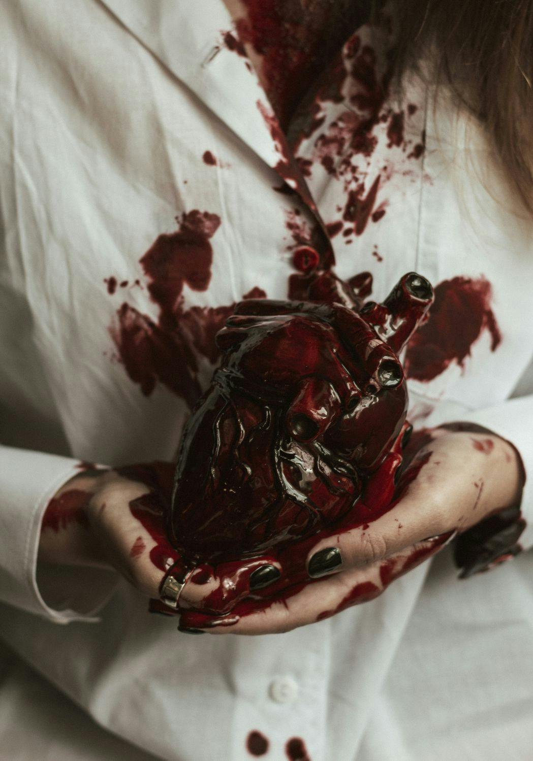 A woman in a lab coat holding a human heart
