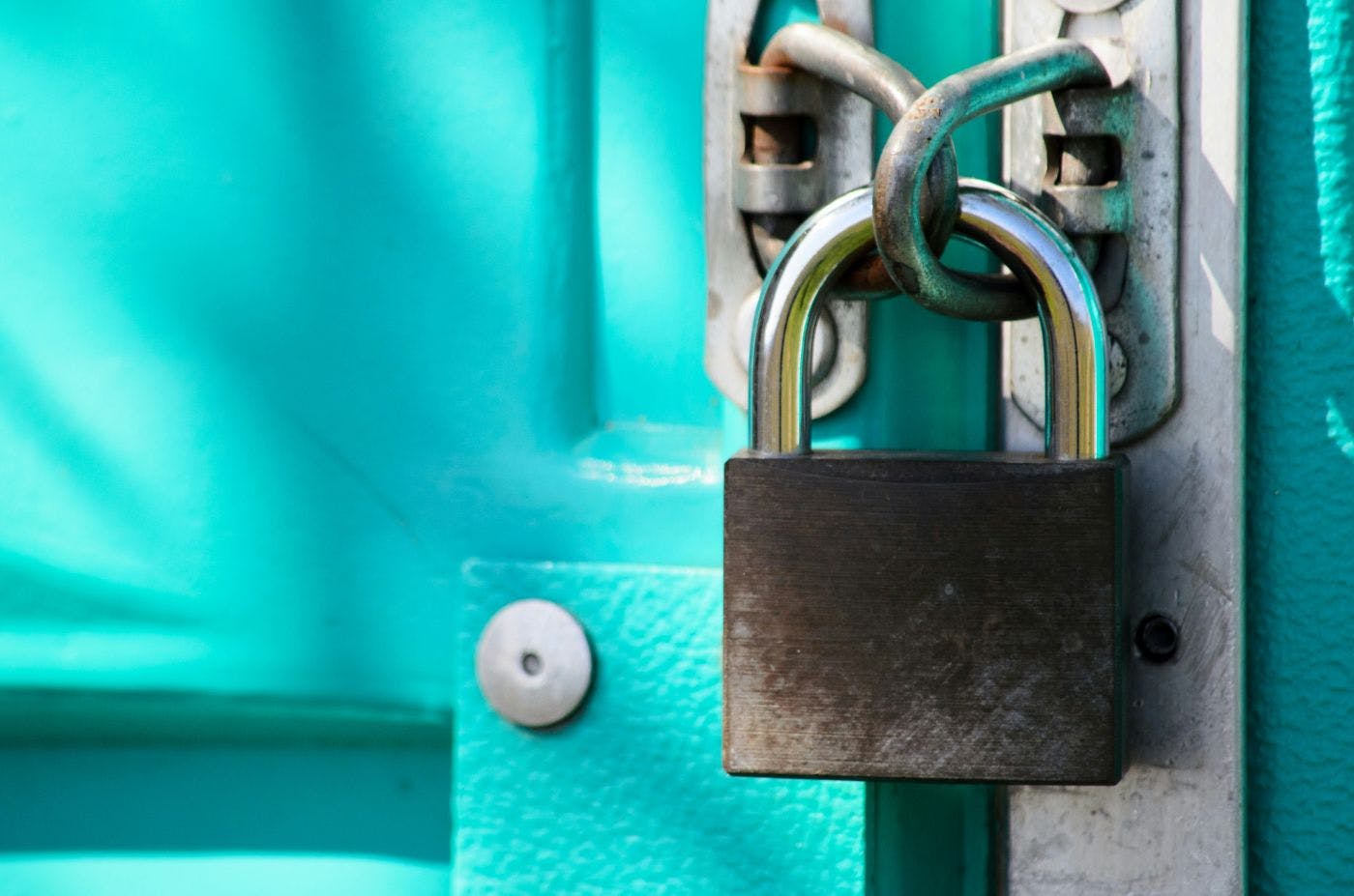 Close up of a padlock on a teal door