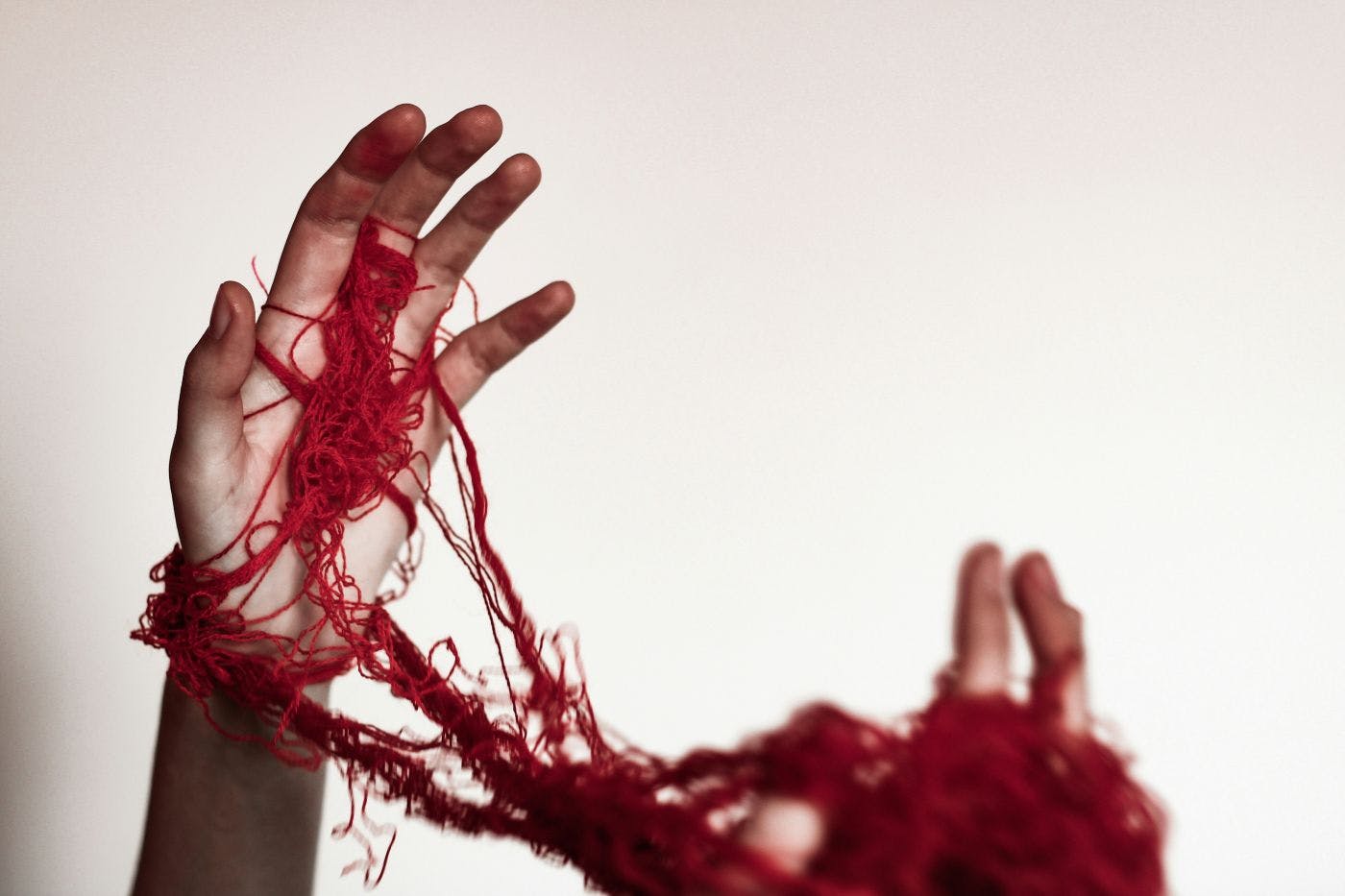 A person's hands wrapped up in red yarn