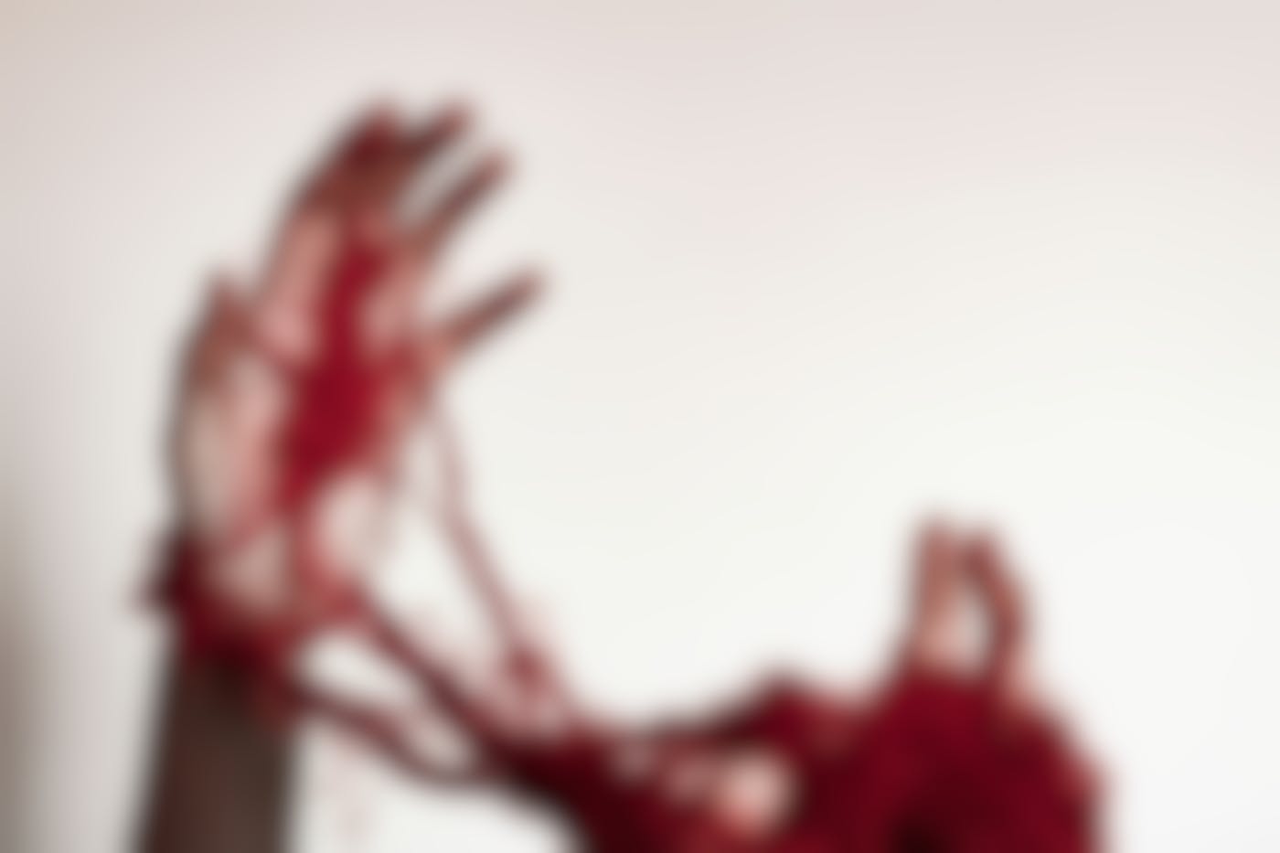 A person's hands wrapped up in red yarn